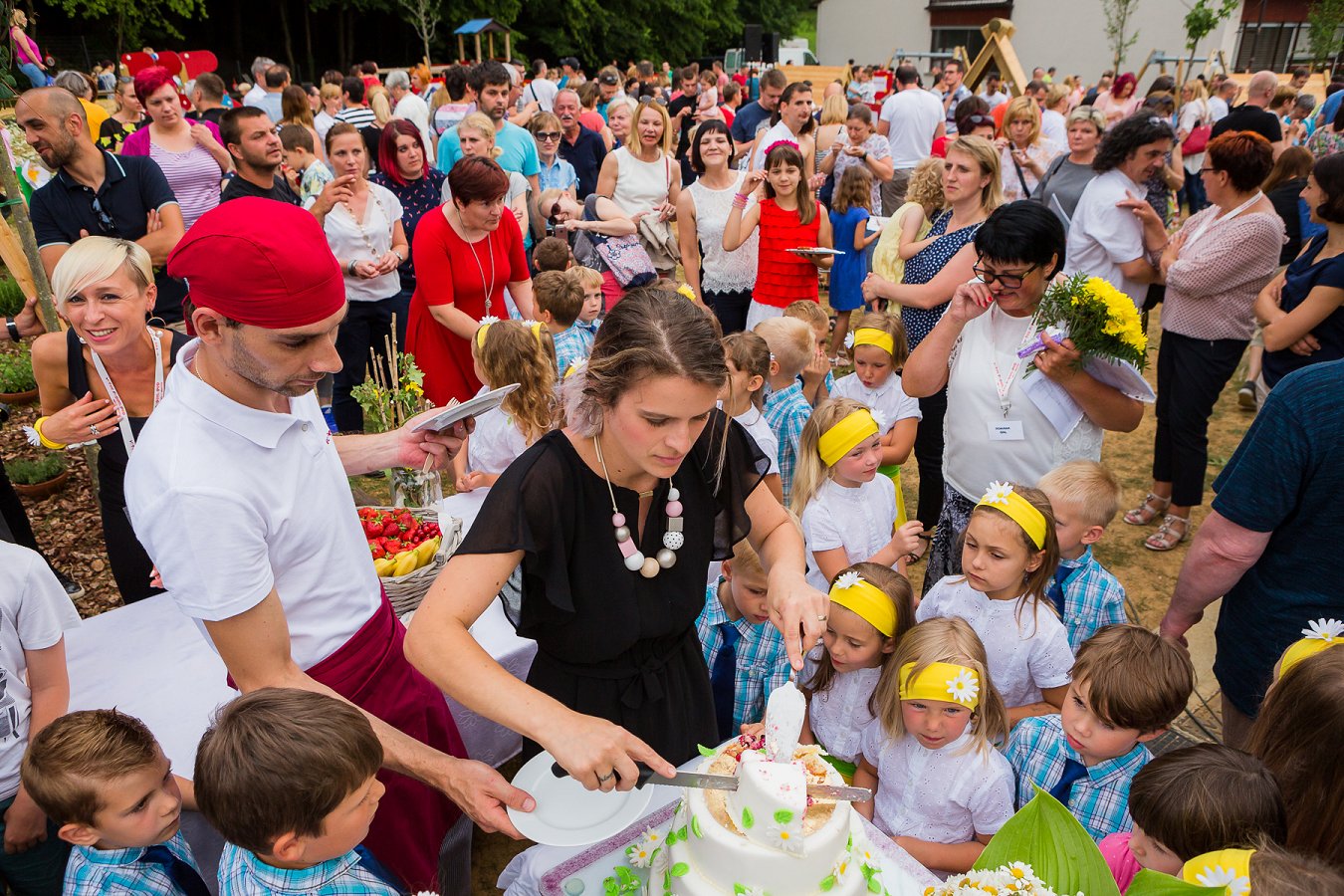 Razrez torte, v ozadju otroci in starši - vrtec Pedenjped