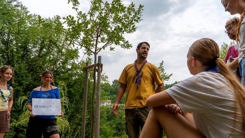 Na fotografiji so mladi taborniki z gozdarjem Gorjanski taborniki se pripravljajo na izvajanje veščine Prijatelj gozda